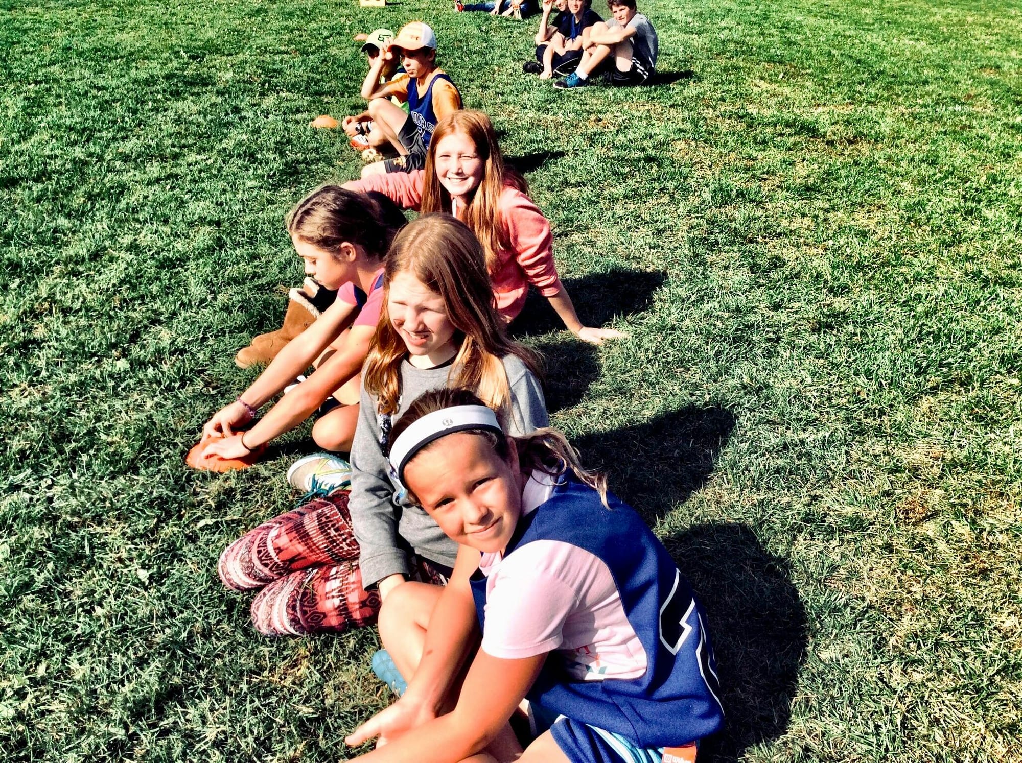 Children sit in a field in a straight line. April is Child Abuse Prevention Month.