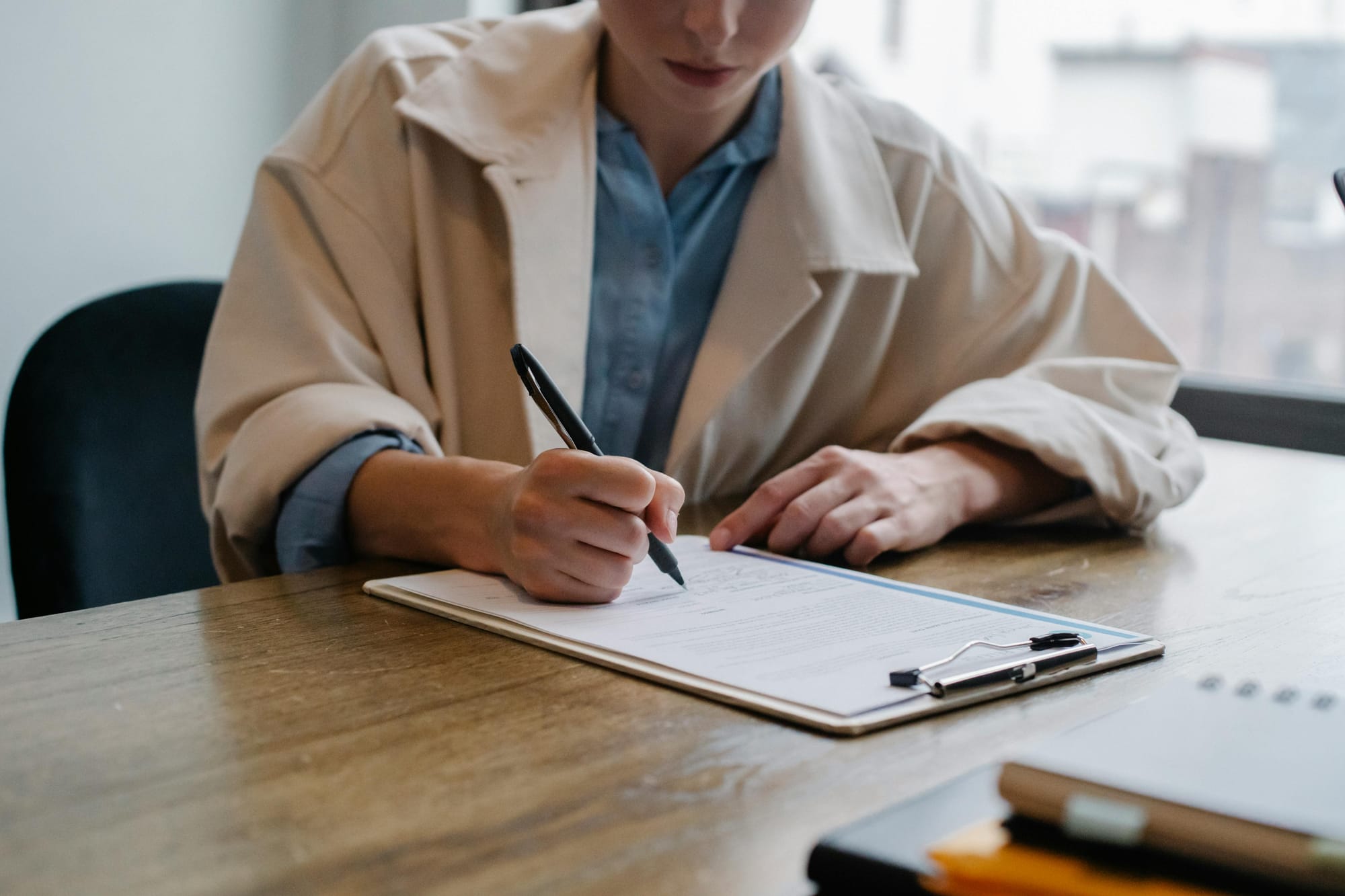 A woman fills out an application on a clipboard. The school district will be holding a MassHealth application assistance event on April 29.