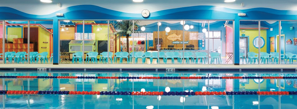 A swimming pool with chairs set up on the other side of a glass wall for observation