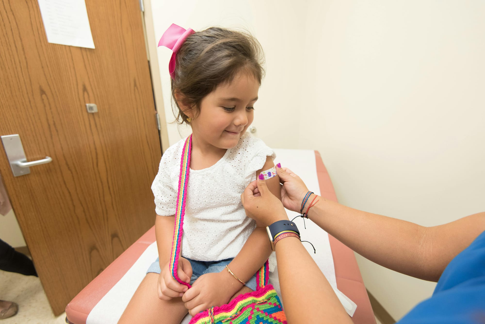 a young girl receiving a bandage on her arm after a vaccination