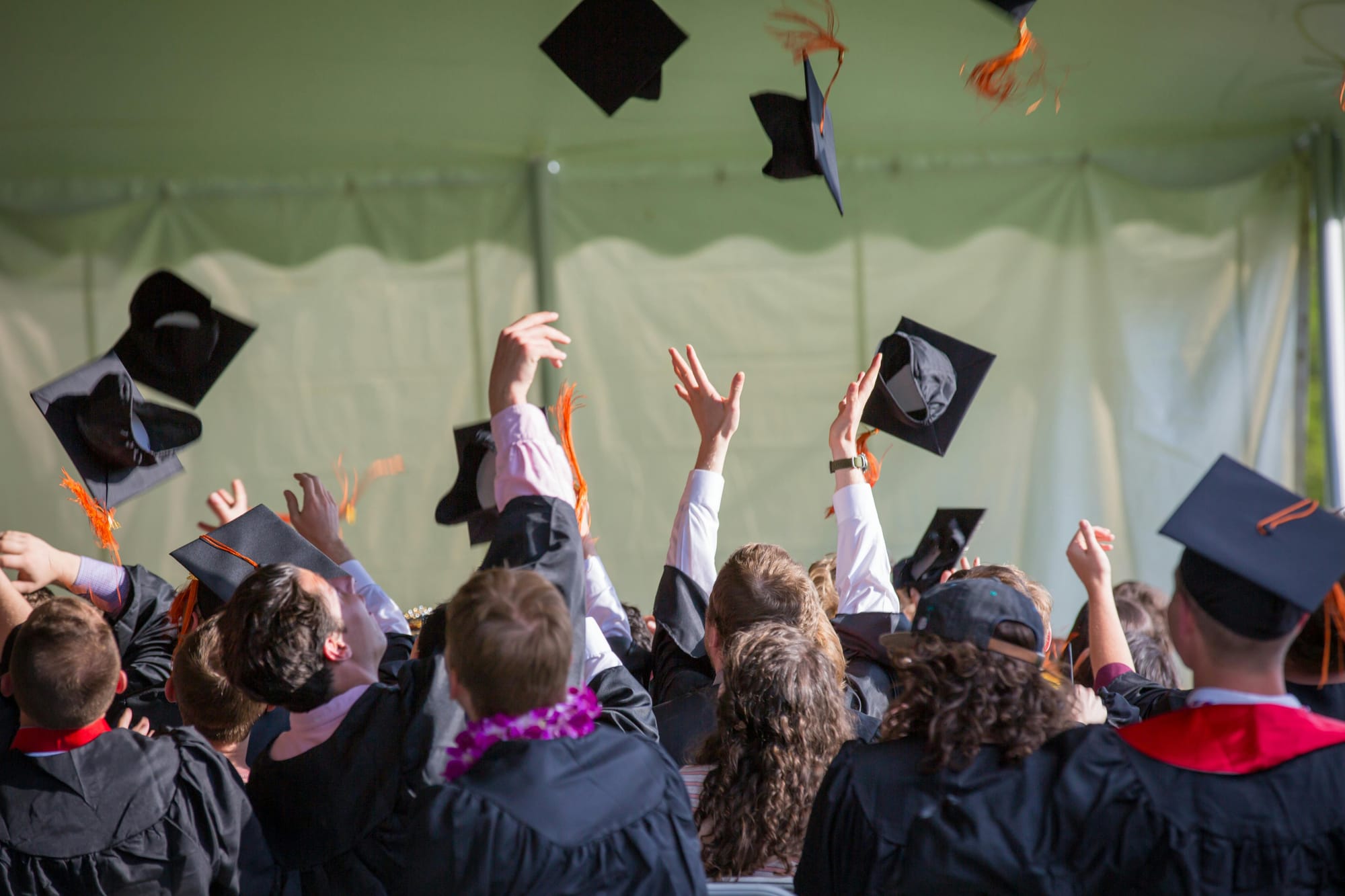 Graduates throwing their graduation caps into the air. 