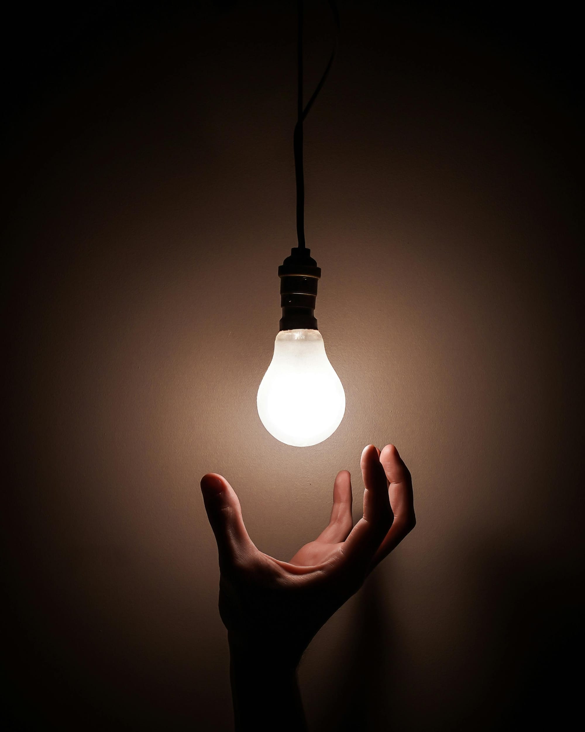 A hand reaching up to change a lightbulb.