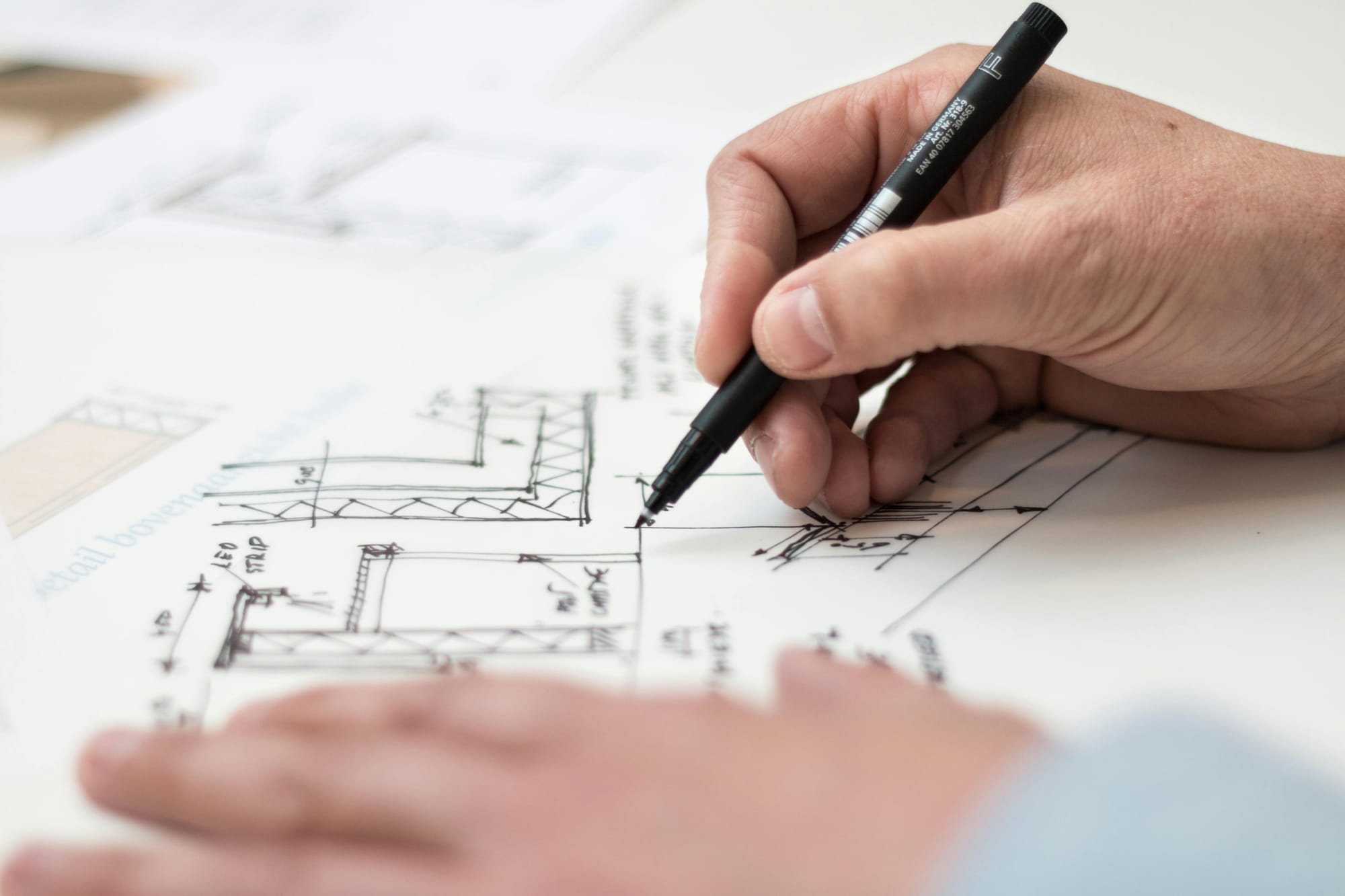 Person Holding Black Pen and working on architectural designs.