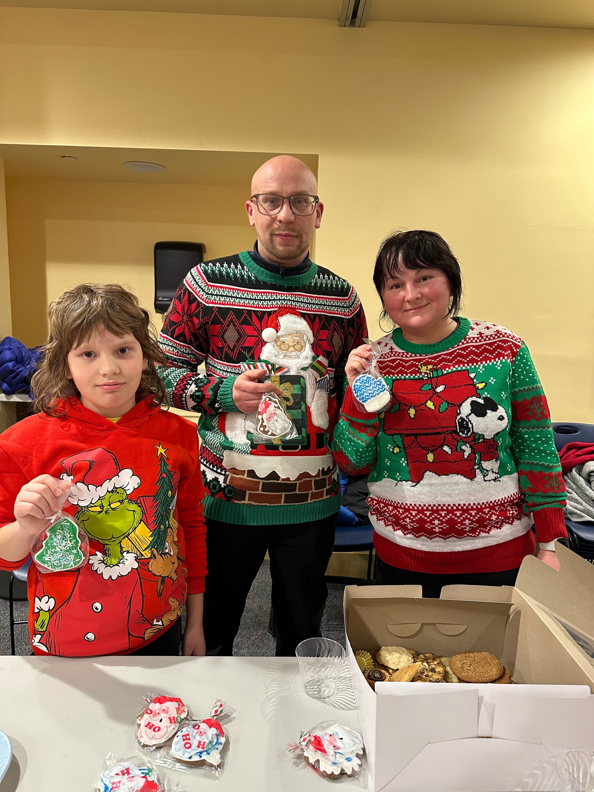 The Averin/Averina family holding their decorated cookies and wearing festive sweaters